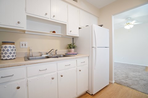 A kitchen with white cabinets and a white fridge.