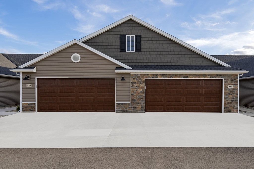 A house with two garages and a driveway in front.