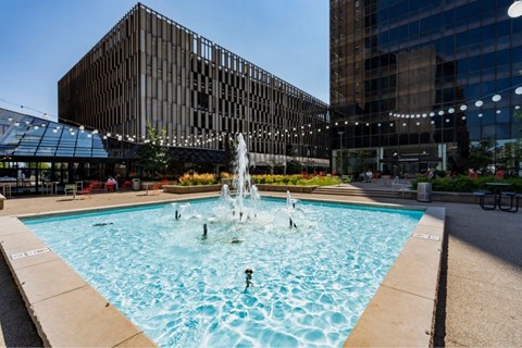 A fountain in the middle of a pool surrounded by buildings.