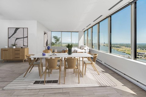 A dining room with a table and chairs with a view of the water.