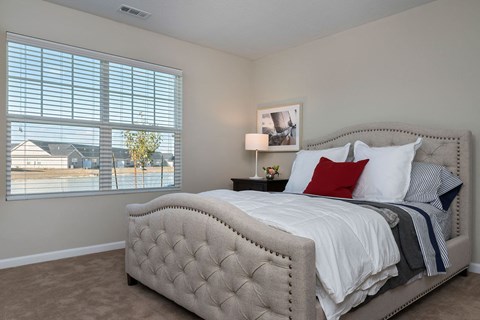 A bedroom with a large bed and a window with blinds.