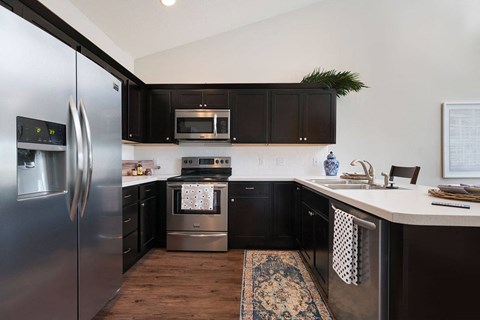 A modern kitchen with a stainless steel refrigerator and black cabinets.