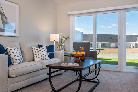 A living room with a grey couch, a coffee table, and a large window.