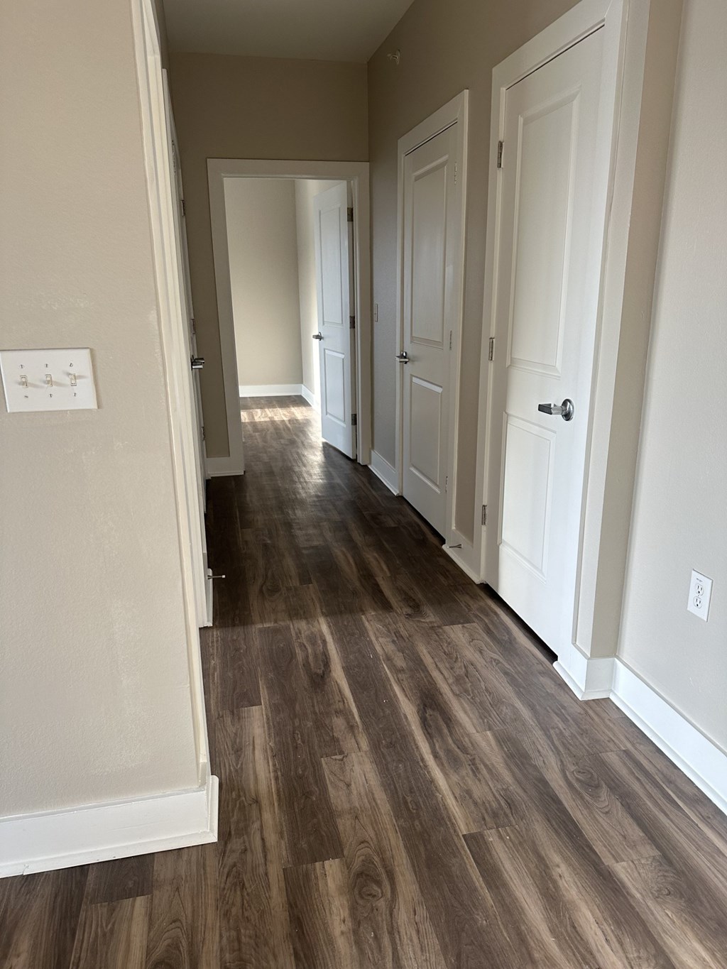 A hallway with wood floors and white doors.