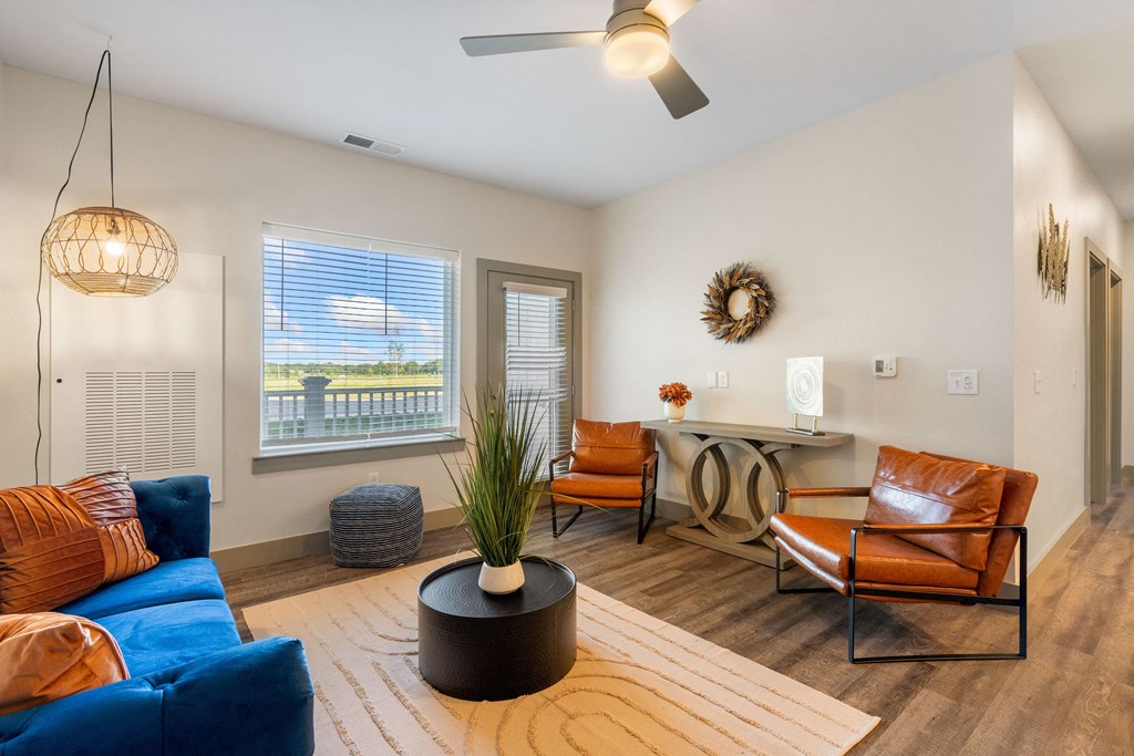 a living room with a blue couch and chairs and a desk with a window at 41 North Apartments, Fort Wayne, 46835