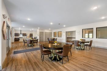 a large community room with a dining area and a kitchen with a table and chairs at 41 North Senior Living Apartments, Indiana 46835