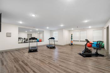 a gym with treadmills and weights in a room with white walls and floors at 41 North Senior Living Apartments, Fort Wayne, 46835