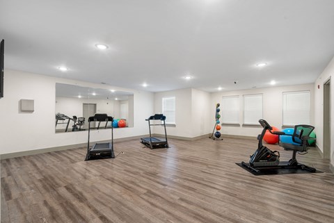 a gym with treadmills and weights in a room with white walls and floors at 41 North Apartments, Indiana, 46835
