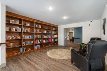 a library with a black leather chair and a book shelf at 41 North Senior Living Apartments, Fort Wayne, IN
