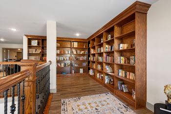 a library with wooden shelves and a staircase at 41 North Senior Living Apartments, Fort Wayne, IN, 46835