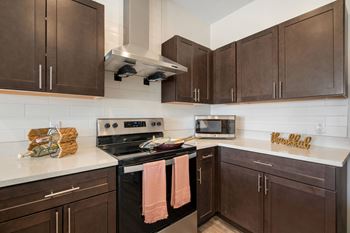 a kitchen with brown cabinets and stainless steel appliances and white countertops at 41 North Senior Living Apartments, Fort Wayne, Indiana