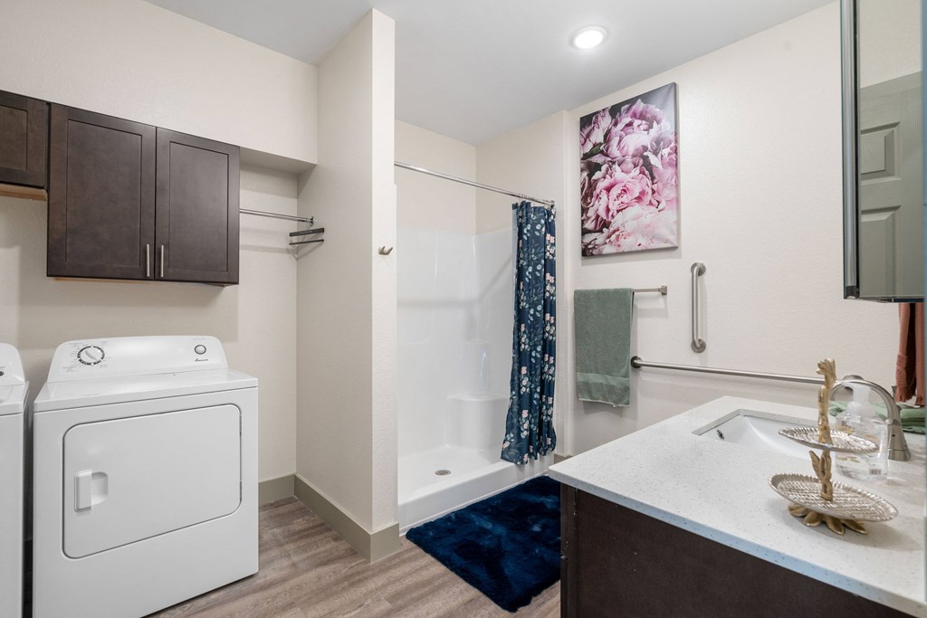 a white washer and dryer in a bathroom with a shower and a sink at 41 North Apartments, Indiana