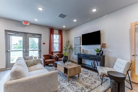 A living room with a couch, chairs, and a television.
