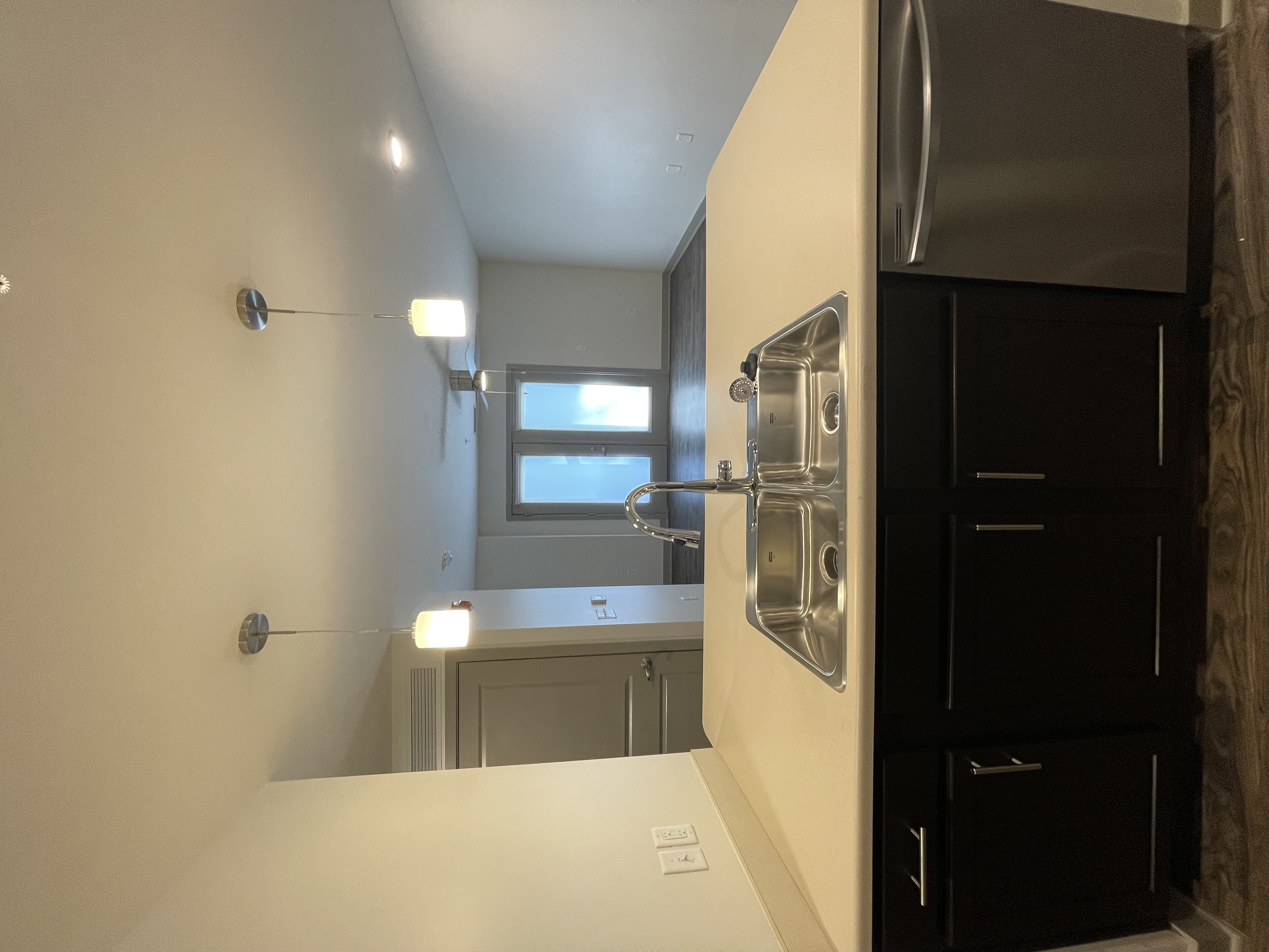 A modern kitchen with black cabinets and stainless steel appliances.