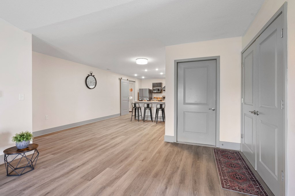 a living room and dining room with white walls and wood flooring at Morada at Maysville, Fort Wayne