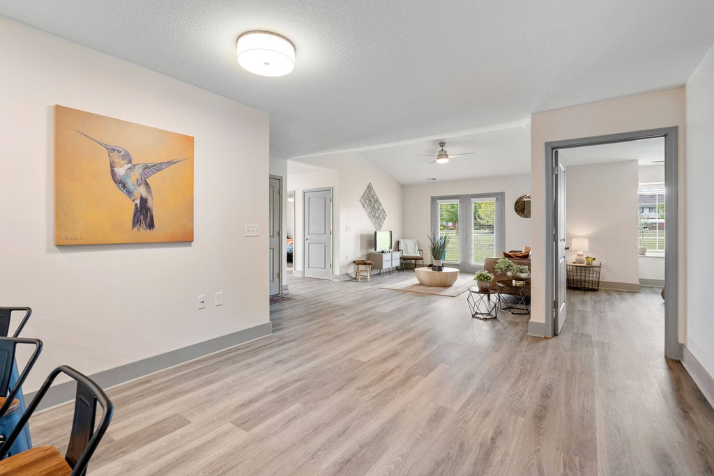 the living room and dining room in a new home with white walls and wood floors at Morada at Maysville, Fort Wayne, IN