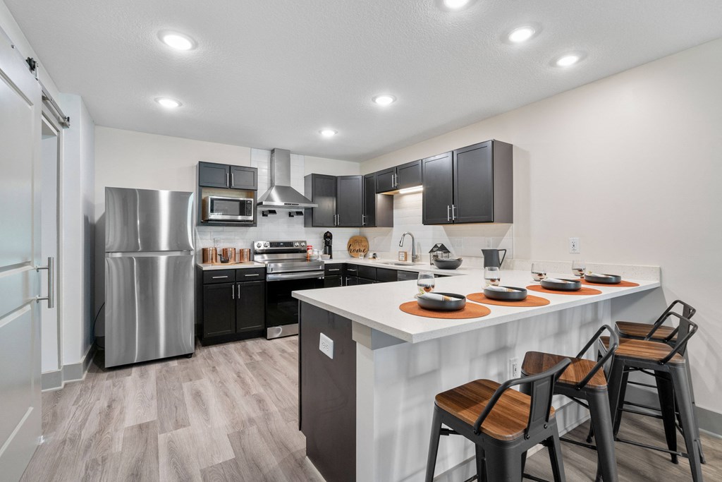 redesigned kitchen with stainless steel appliances and a large island with stools at Morada at Maysville, Fort Wayne, IN 46815