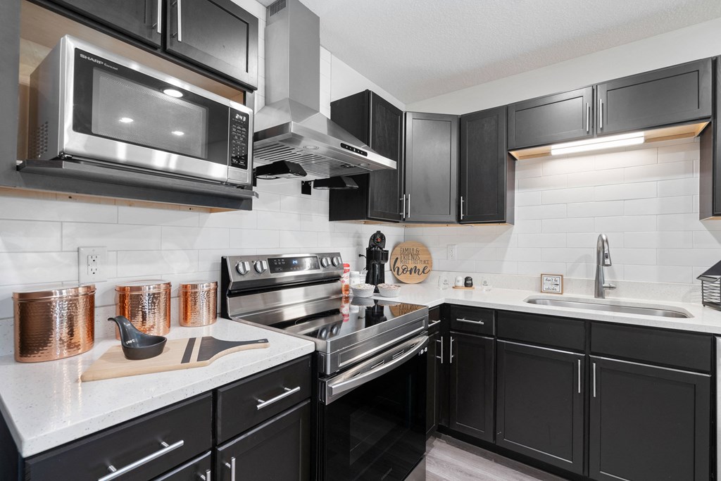 a kitchen with black cabinets and stainless steel appliances and a microwave at Morada at Maysville, Fort Wayne, 46815