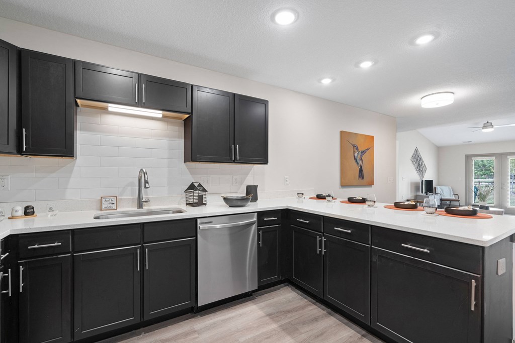 a large kitchen with black cabinets and white counter tops and a sink at Morada at Maysville, Fort Wayne Indiana