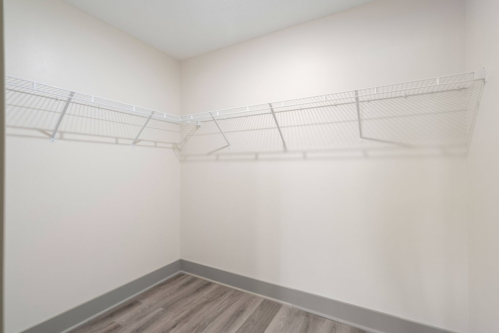 an empty closet with white walls and wooden floors and a wire rack on the wall at Morada at Maysville, Fort Wayne