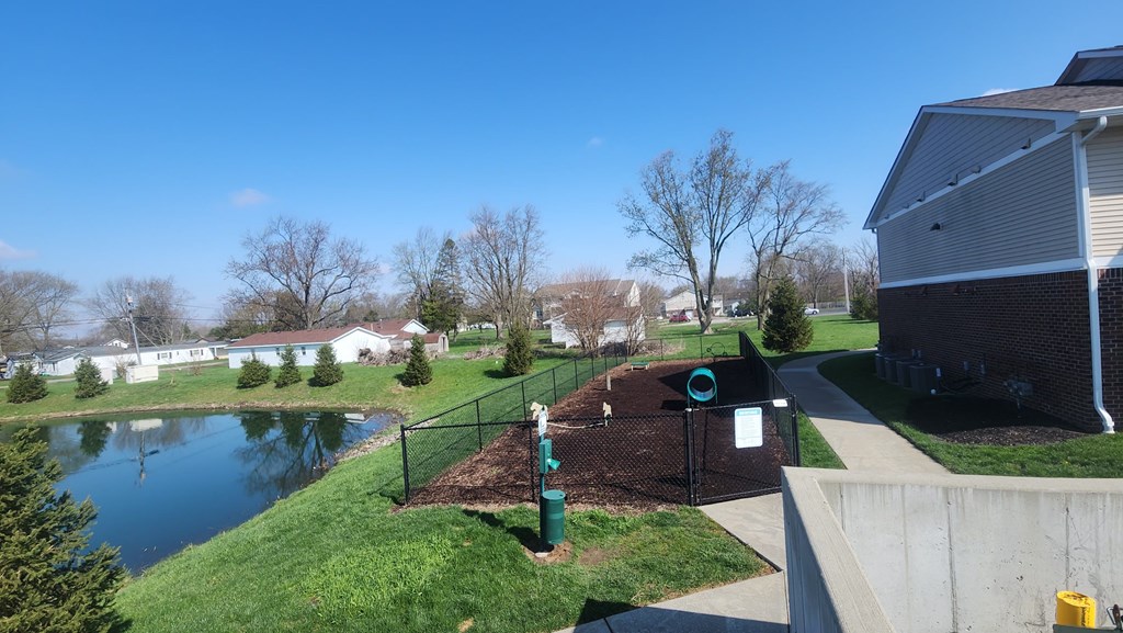 A park with a playground and a pond in the background.