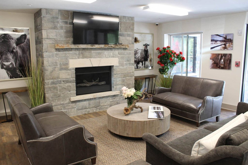 a living room with a stone fireplace and leather furniture  at Roaring Fork Apartments, Colorado, 81621