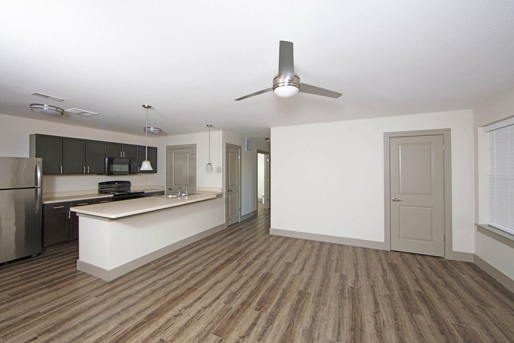 an empty living room with a kitchen and a ceiling fan  at Gladstone Apartments, Indiana, 47201