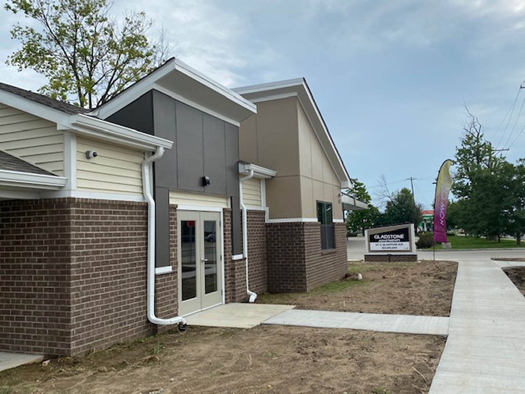 the front entrance of a brick building with a sidewalk  at Gladstone Apartments, Columbus, IN