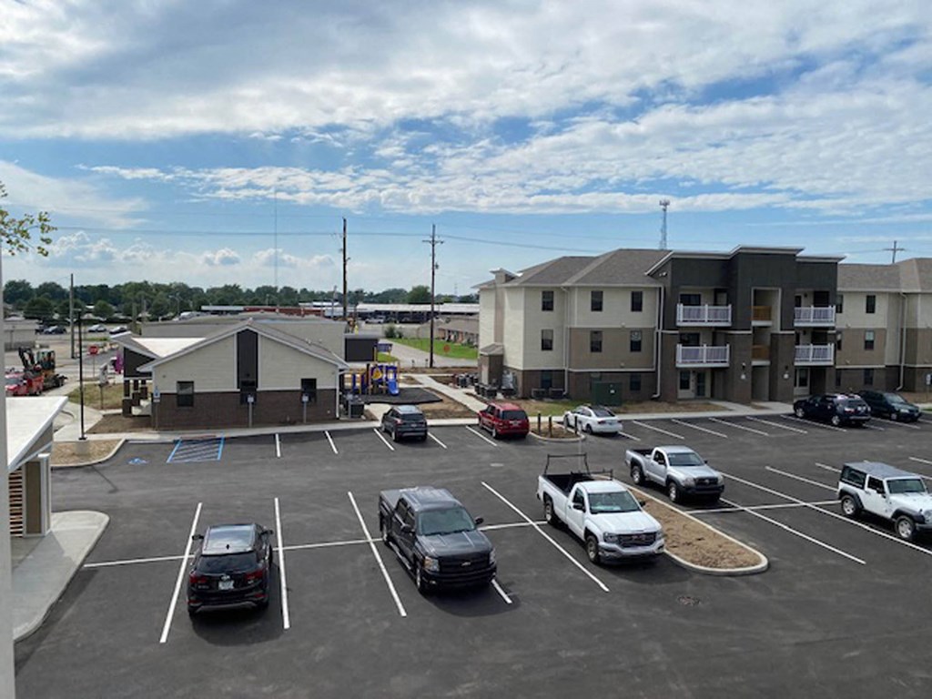 a parking lot filled with cars in front of an apartment building  at Gladstone Apartments, Columbus, IN
