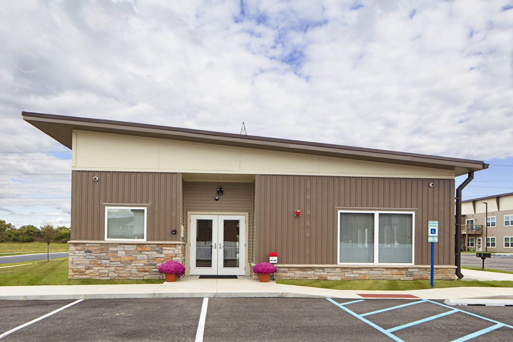 the front of a brown building with a parking lot