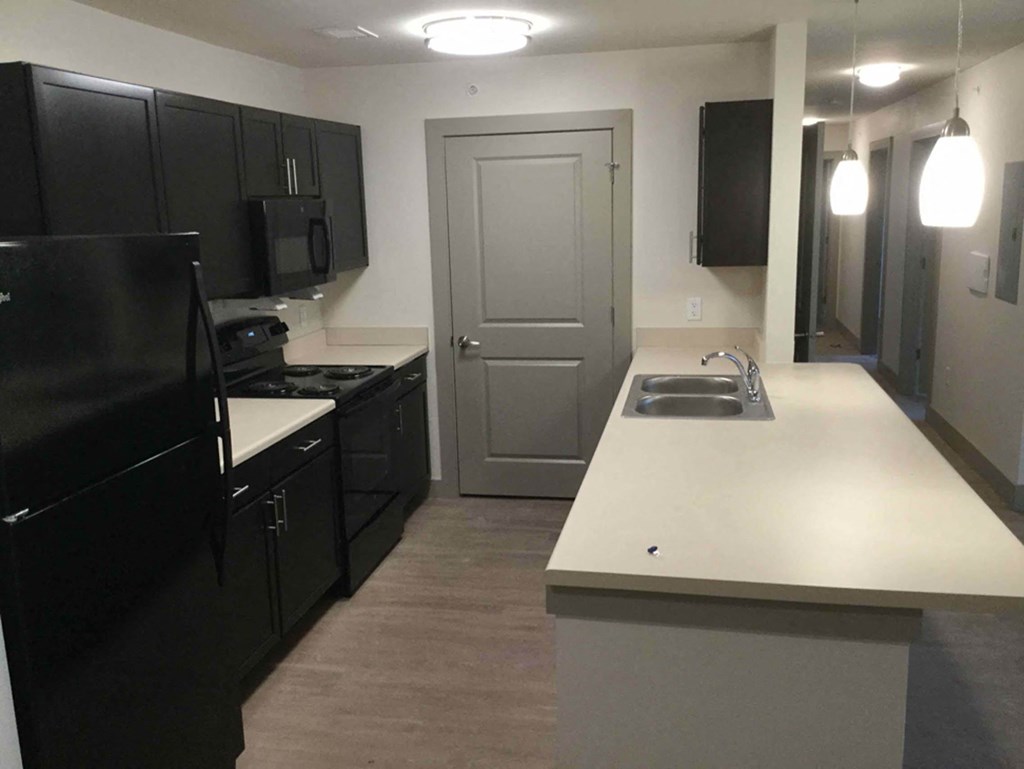 a kitchen with black cabinets and a white counter top and a door
