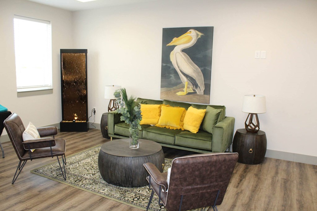 a living room with a green couch and a painting of a bird  at Haven Homes Apartments, LP, Indiana, 46168