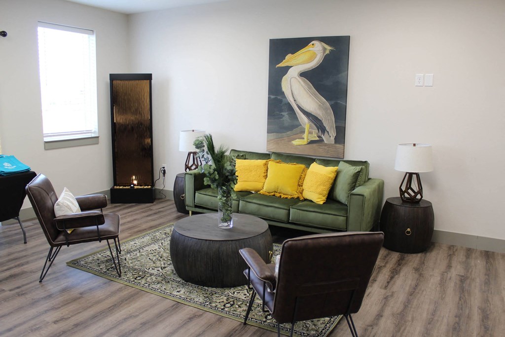 a living room with a green couch and a painting of a bird  at Haven Homes Apartments, LP, Plainfield, IN, 46168