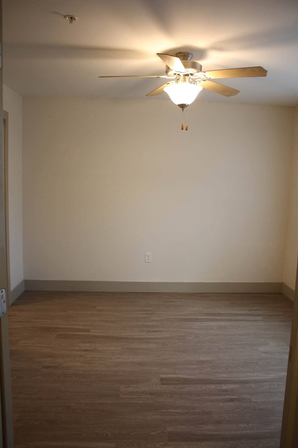 an empty room with a ceiling fan and wood floors at Salem Place Apartments, Indiana