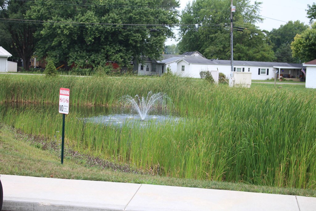 a fountain in the middle of a grass field at Salem Place Apartments, Daleville, IN