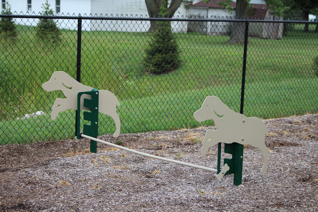 two wooden dogs on a seesaw in front of a fence at Salem Place Apartments, Daleville, 47334