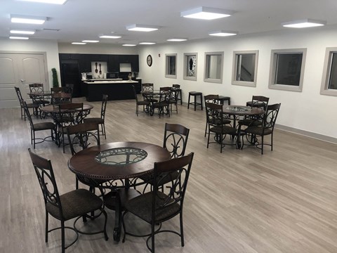 a large room with tables and chairs and a kitchen