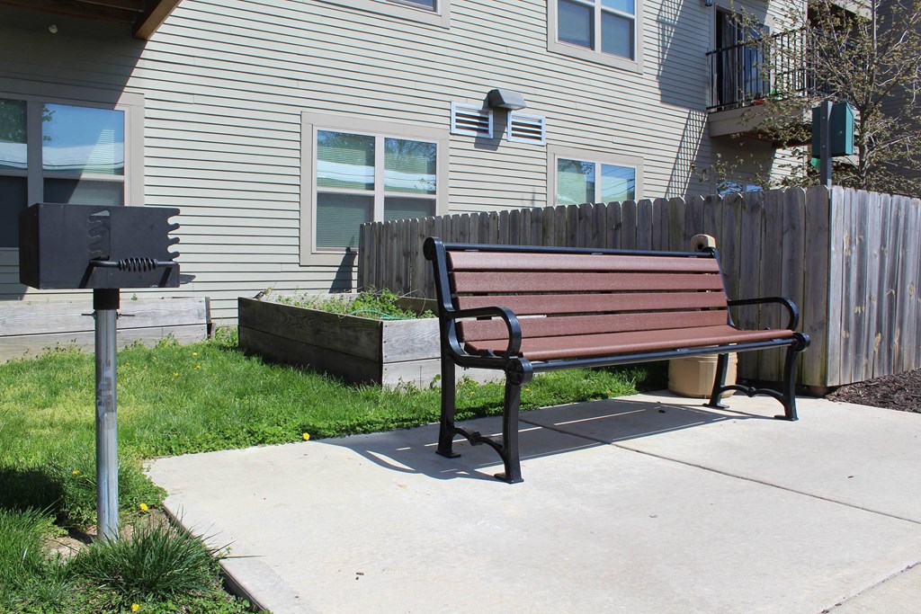a wooden bench sitting on a sidewalk next to a mail box  at North Harrison Senior Apts, Shelbyville, IN, 46176