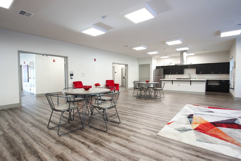 a room with tables and chairs and a kitchen at SouthPointe Village Apartments, LP, Fishers, 46038