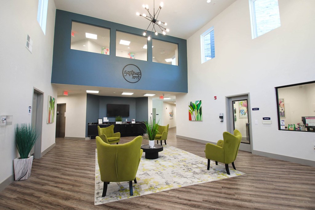 a large lobby with yellow chairs and a blue accent wall at SouthPointe Village Apartments, LP, Indiana, 46038