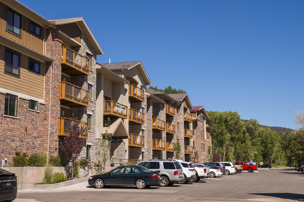 a row of apartments with cars parked in a parking lot  at Roaring Fork Apartments, Basalt, 81621