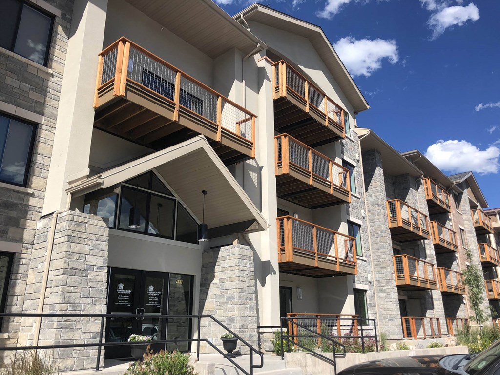 the facade of a condo building with wooden balconies and stone pillars  at Roaring Fork Apartments, Basalt, Colorado