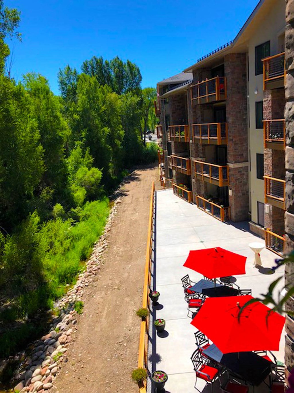 a balcony with tables and umbrellas next to a building  at Roaring Fork Apartments, Basalt, Colorado