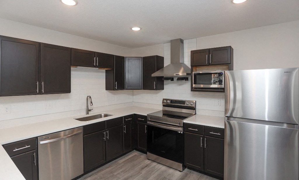 a kitchen with stainless steel appliances and black cabinets a kitchen with stainless steel appliances and black cabinets at Morada at Maysville, Fort Wayne, IN 46815