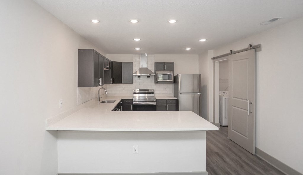 a kitchen with a white counter top and a stainless steel refrigerator