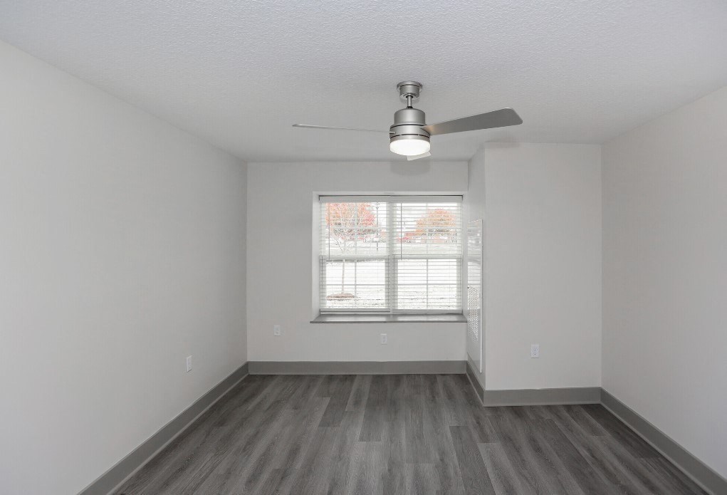 an empty room with white walls and wood floors and a ceiling fan