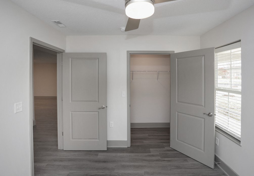 an empty bedroom with two doors and a closet