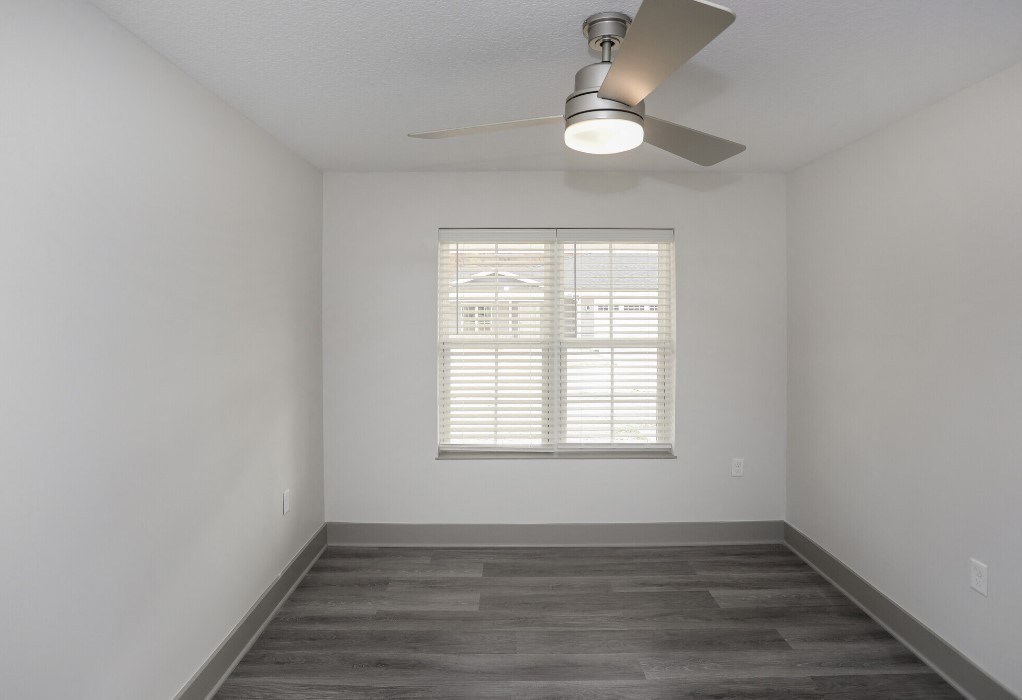 an empty room with a window and a ceiling fan