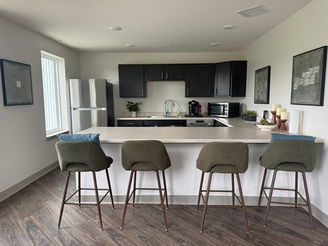 A kitchen with a bar area and three bar stools.