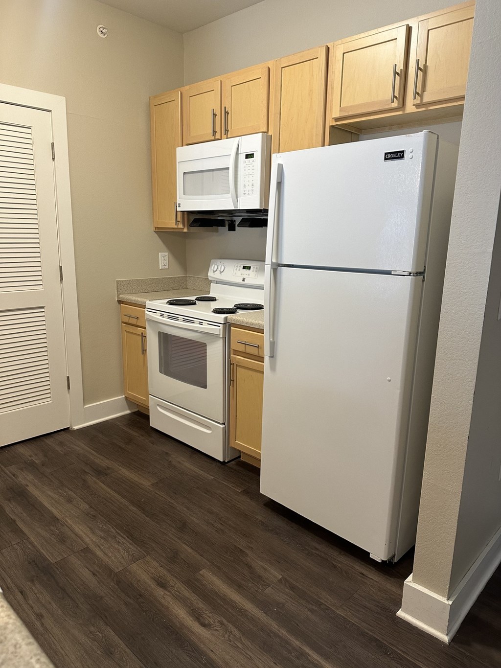 A kitchen with a white refrigerator, white stove, and white microwave.
